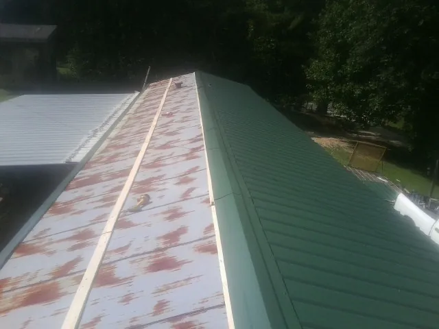 Old rusted panels beside newly installed green metal roofing — Wind Damage Roof Repair by Roofing Brothers in Longport