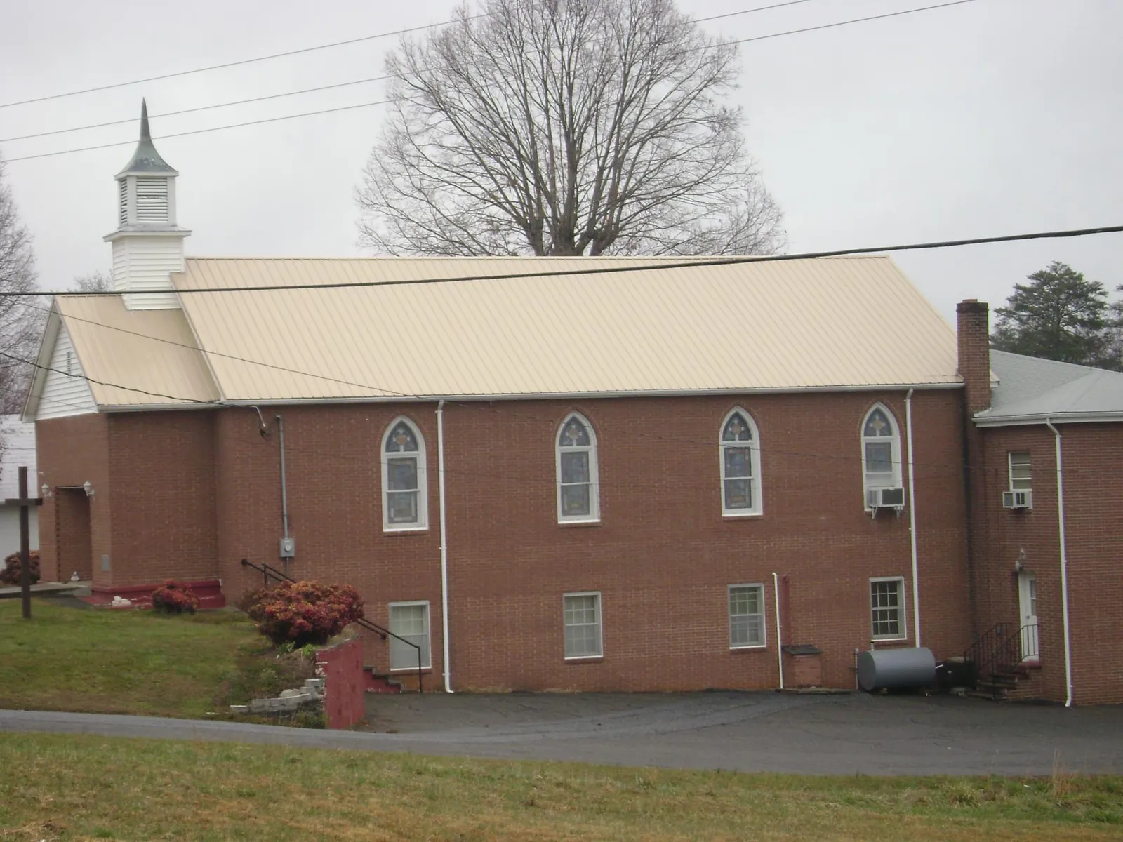 New tan metal roof on a brick church with a white steeple in Longport