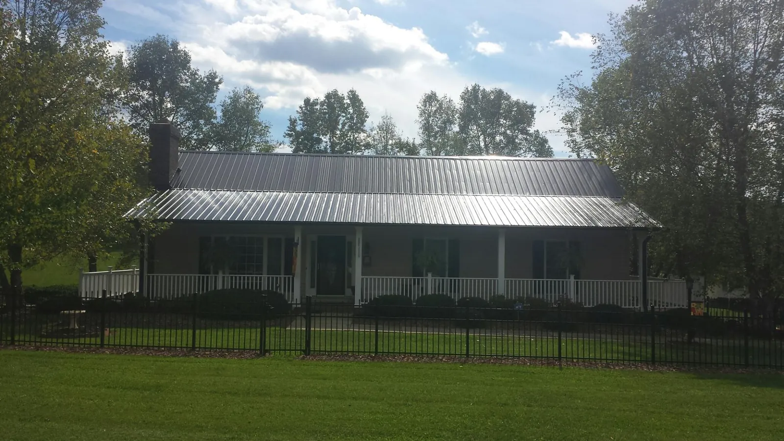 Gray metal roof on a brick ranch with a full width front porch — Gutter Guard Installation work by our crew in Longport