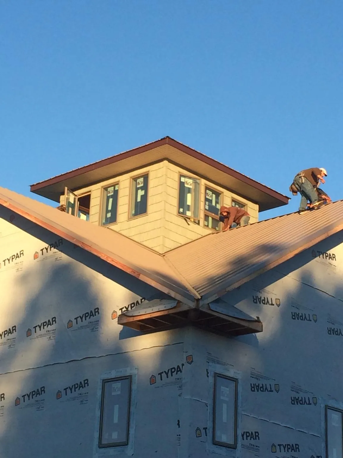 Roofers working around a rooftop cupola on a new metal roof at sunset — Roof Waterproofing in Longport by Roofing Brothers